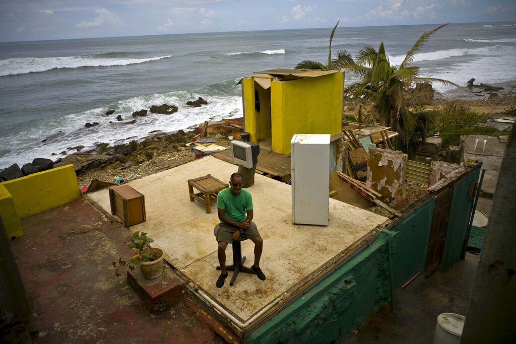 Roberto Figueroa Caballero sits on a small table in his home in Puerto Rico destroyed by Hurricane Maria.