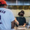 A Chipotle Mexican Grill worker prepares a meal for a customer waiting in line.