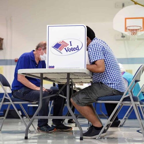  People sit at a table as they cast their ballots during primary voting. 
