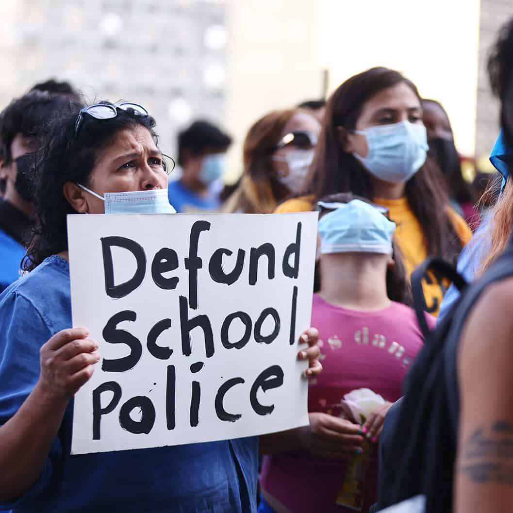 A protester holds up a sign that says 'defund school police' outside the Unified School District headquarters in Los Angeles.