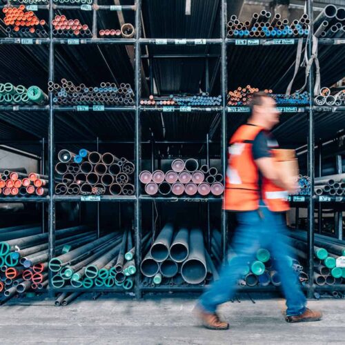  A person walks past pipes at a warehouse. 