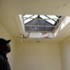 A photo of a D.C. Housing Authority maintenance supervisor looking at water damage to a stairwell skylight in a public-housing complex